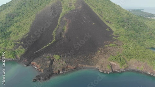 Aerial: flying over Banda Islands active volcano Gunung Api lava flows Maluku Indonesia lush green forest turquoise water coral reef scenic travel destination. Native cinelike D-log color profile photo