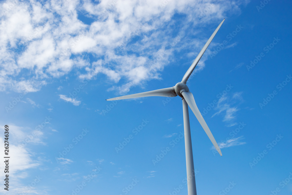 Windmill against blue sky, renewable electric energy production, low angle view.