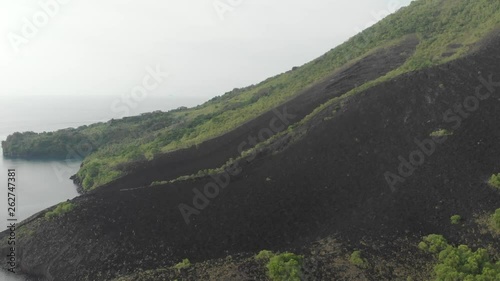 Aerial: flying over Banda Islands active volcano Gunung Api lava flows Maluku Indonesia lush green forest turquoise water coral reef scenic travel destination. Native cinelike D-log color profile photo