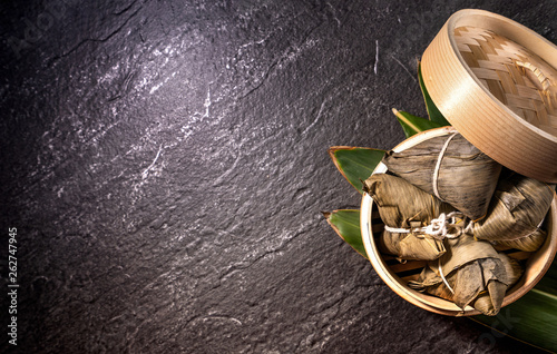 Close up, copy space, top view, flat lay. Famous asian chinese tasty handmade food in duan wu event, steamed rice dumplings shaped like pyramidal ingredient on black slate photo