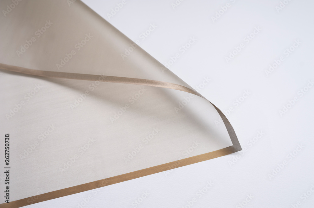 transparent paper corner with golden edges on white background. floristics and packaging concept. golden floral paper sheet