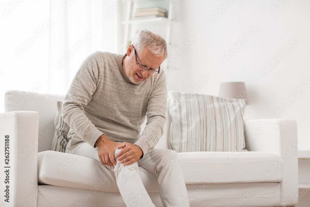 people, health care and problem concept - unhappy senior man suffering from knee ache at home