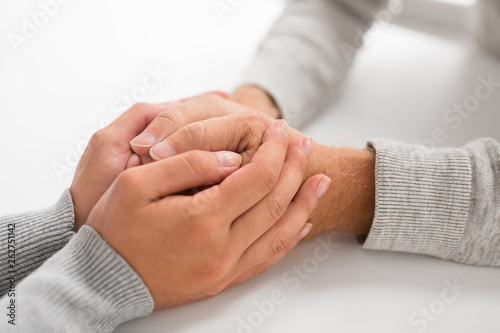 old age  family  care and support concept - close up of young woman holding senior man hands