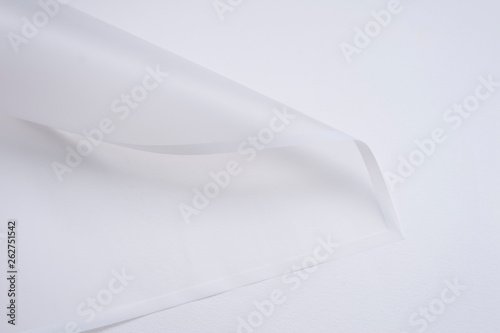 transparent paper corner with white edges on white background. floristics and packaging concept. white floral paper sheet