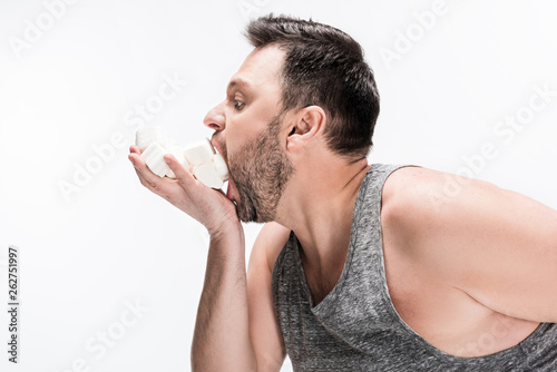 side view of chubby man eating marshmallows isolated on white