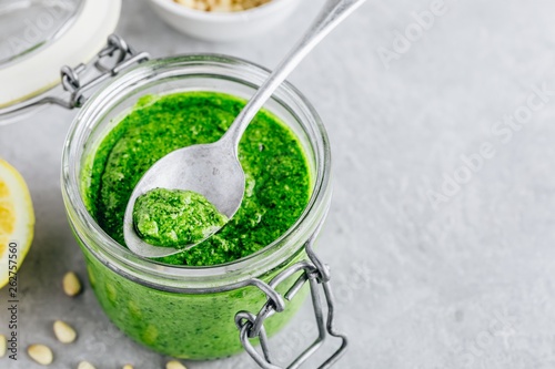Homemade basil pesto sauce in glass jar with parmesan cheese and olive oil
