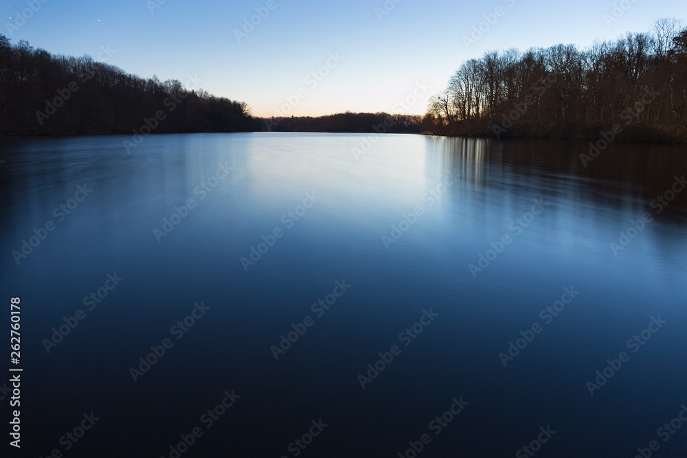 Calm forest lake early in the morning. The Sun slowly rising Calm forest lake early in the morning. The Sun slowly rising