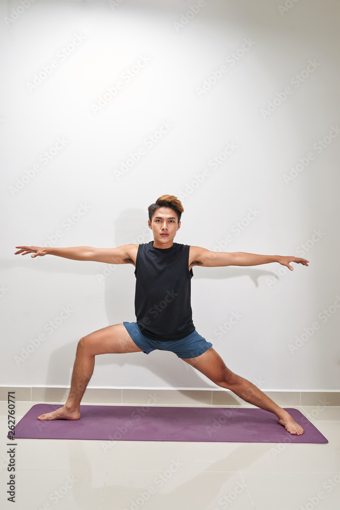 Fitness man plank workout training at white background indoors. Young guy makes exercise. Healthy lifestyle, gymnastics concept