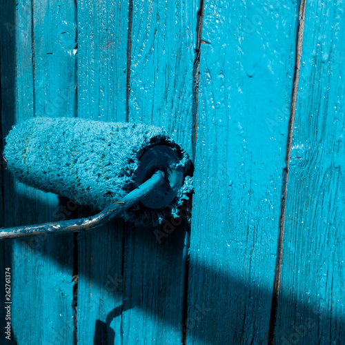 Quadro su tela Man paints a fence in blue. Paint the fence in blue.