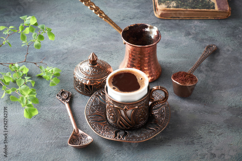 Oriental coffee cooked in traditional Turkish copper coffee pot and  served in a matching cup photo