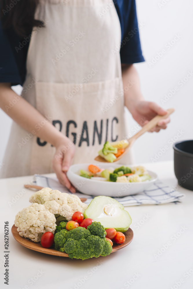 Woman in kitchen cooking stir vegetables on pan and tasting. Woman in kitchen cooking stir vegetables on pan and tasting.