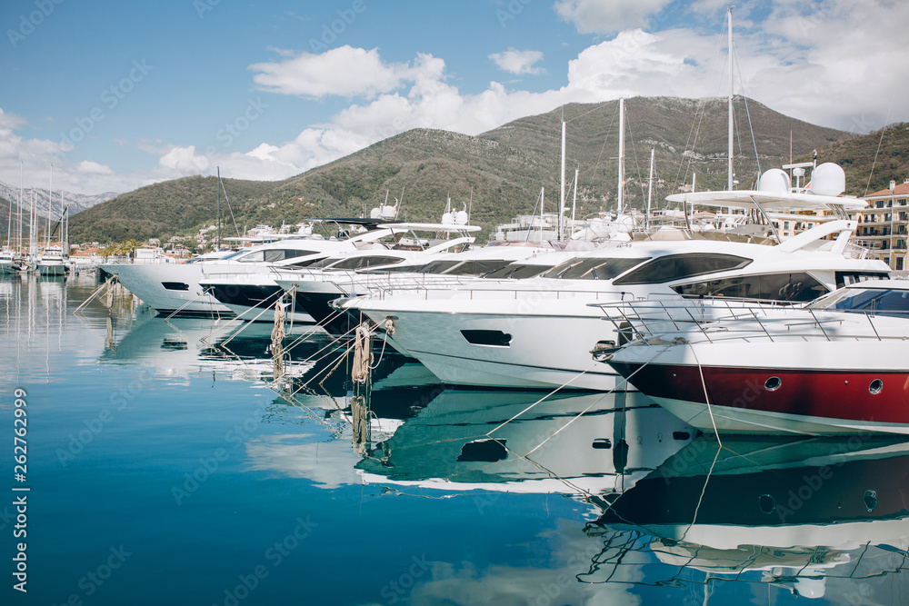 Fototapeta premium Many yachts moored at the coast in Porto Montenegro in Tivat in Montenegro against the backdrop of a beautiful mountain landscape. Summer sea vacation