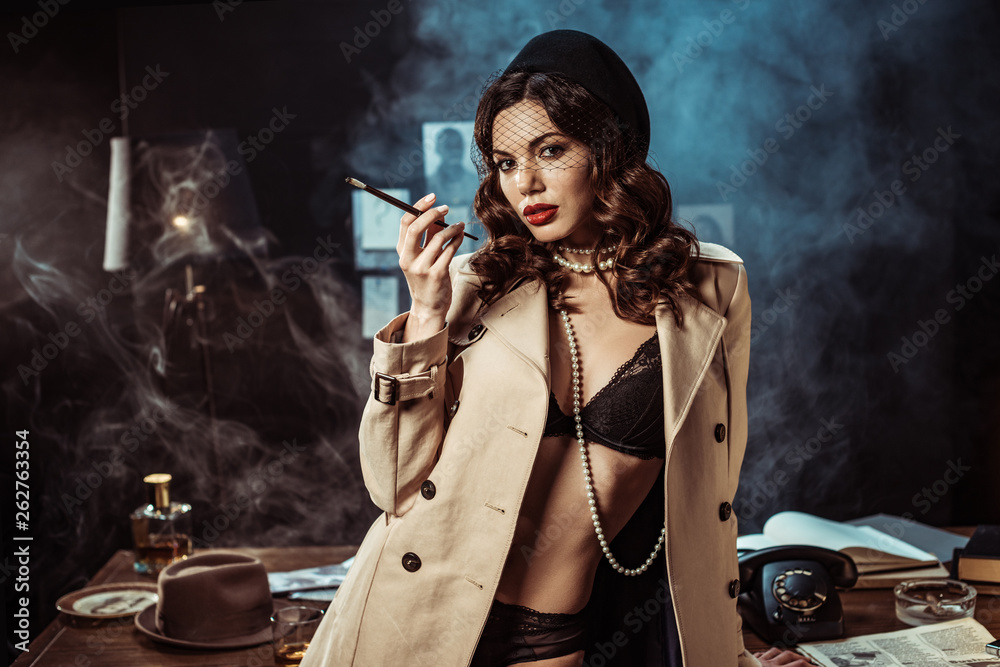 Sexy girl in black lingerie and trench coat holding mouthpiece in dark  office Stock Photo | Adobe Stock