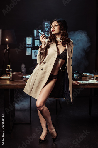 Sexy girl in black lingerie and trench coat holding mouthpiece in dark  office Stock Photo | Adobe Stock