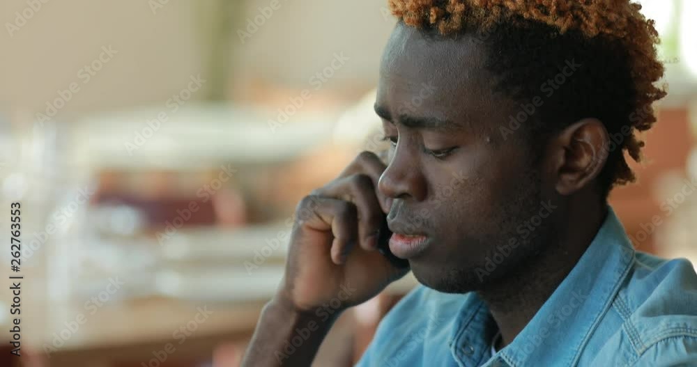 African american businessman or student talking by mobile phone while using laptop computer in cafe African american businessman or student talking by mobile phone while using laptop computer in cafe