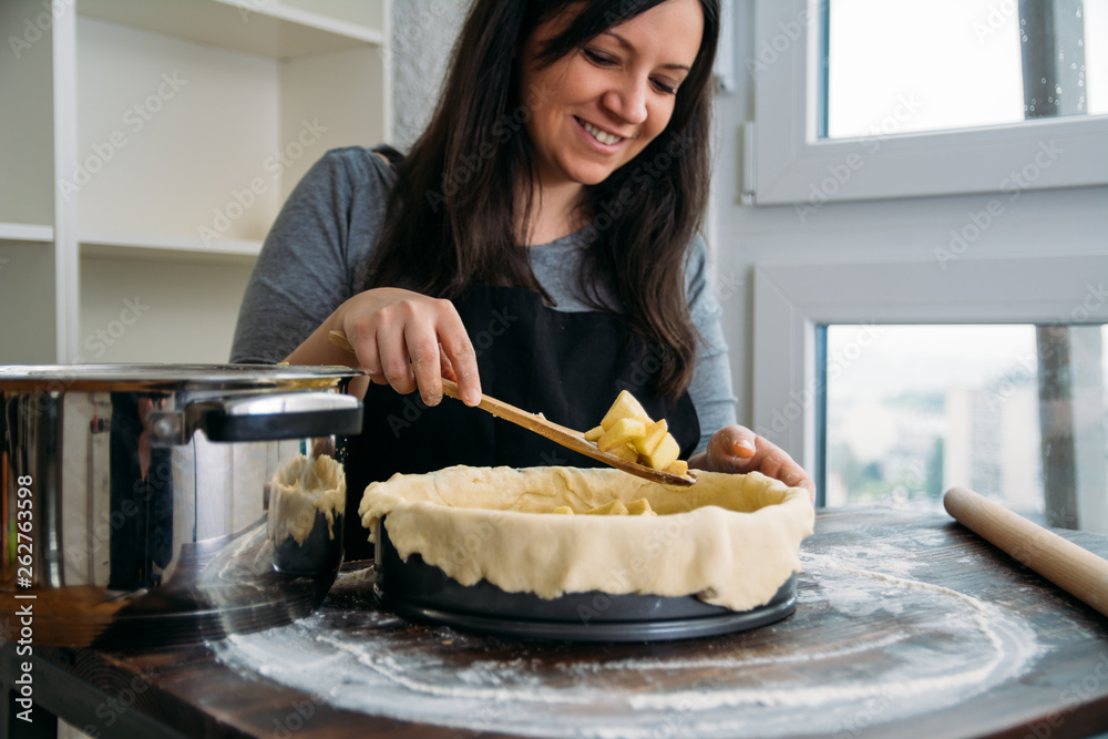 Woman pouring apple filling into baking pan