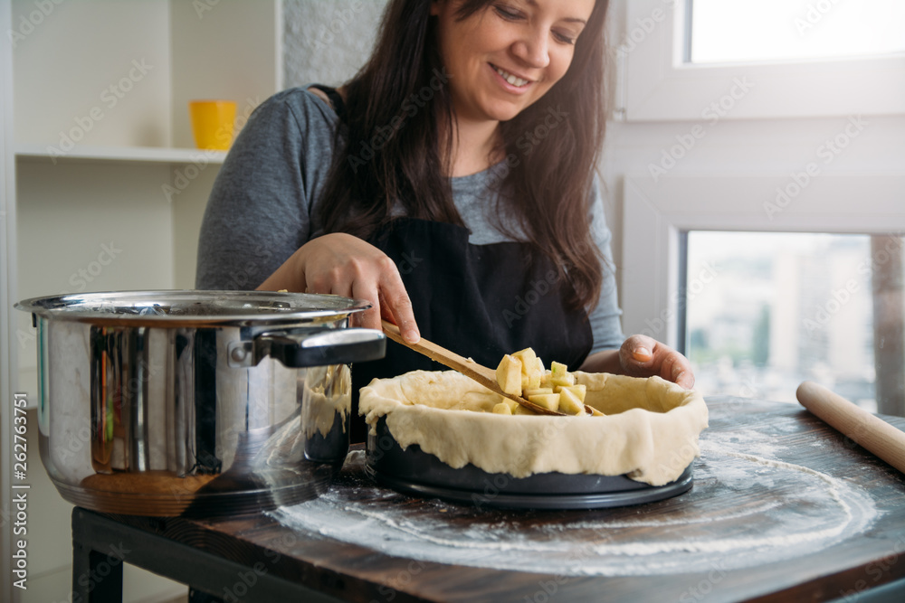 Woman pouring apple filling into baking pan
