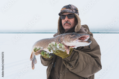 man holding catch winter fishing pike fish