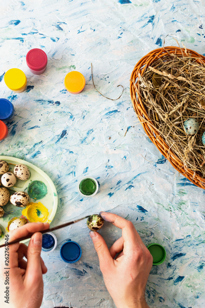 Painting Easter quail eggs on a light multi-colored background. Flat lay