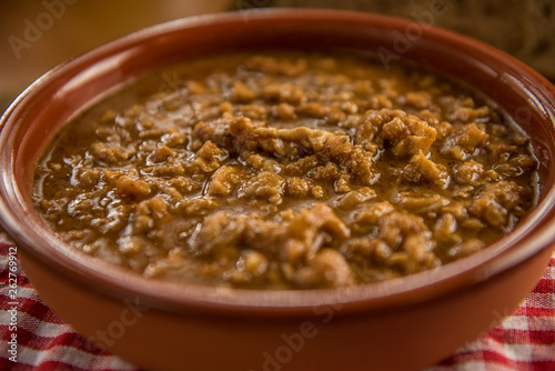 tripe stew sauce in brown ceramic pot on a wood table 