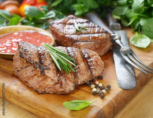 grilled beef steak on a cutting board with spices .