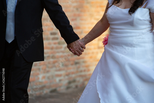 A close up view on the holding hands of a just married bride and groom, romantic wedding concept. © Alessandro Grandini