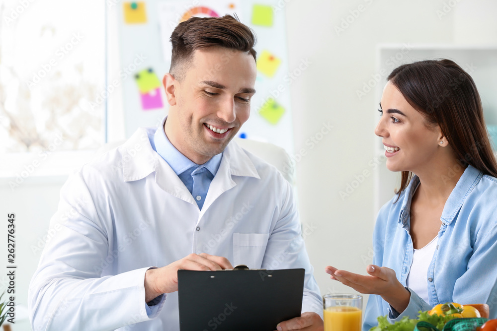 Fototapeta premium Young woman visiting nutritionist in weight loss clinic