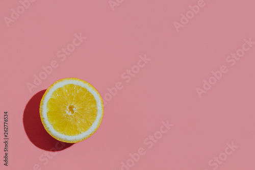 Fresh cutted lemon on a pastel pink background closeup at the left corner of the table