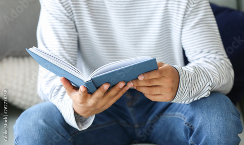 African-American teenage boy reading book at home