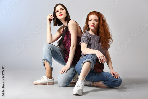 Portrait of fashionable young women on grey background