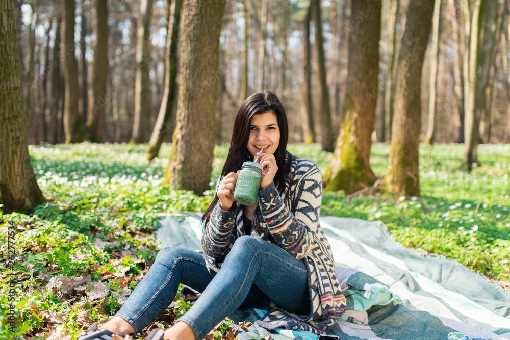 Happy healthy eating girl drinking green smoothie detox outdoors in the wood. Woman on weight loss diet vegan nutrition cleanse. Happy healthy eating girl drinking green smoothie detox outdoors in the wood. Woman on weight loss diet vegan nutrition cleanse.
