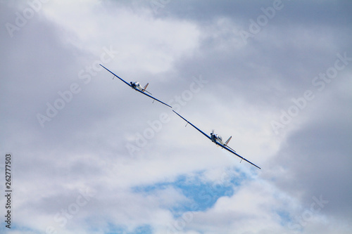 Low angle view of two aerobatic planes performing maneuvers against a cloudy sky. Precision and skill concept.