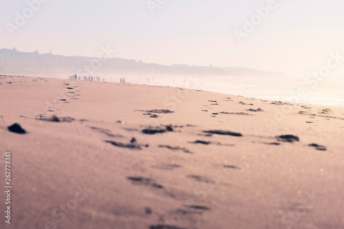 footprints in the sand of the beach covered by fog