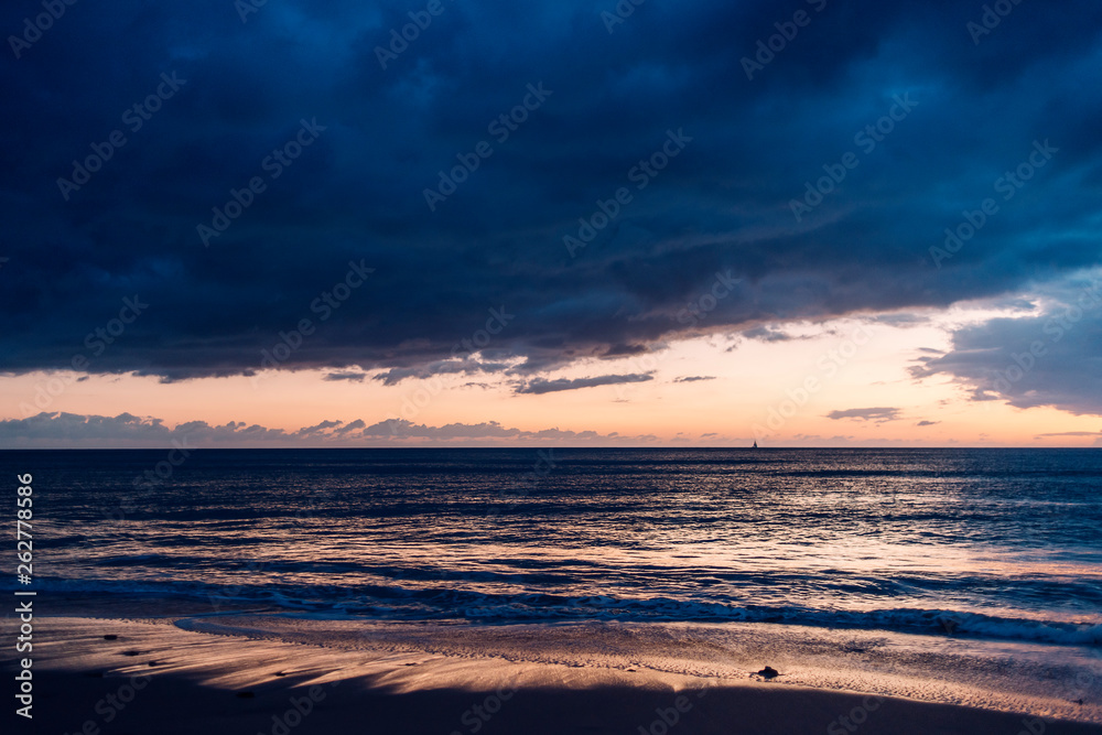 Obraz premium colorful sunset on a beach with stormy sky