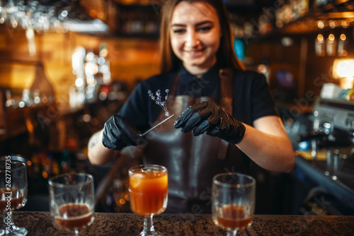 Female bartender holding a glass with coctail