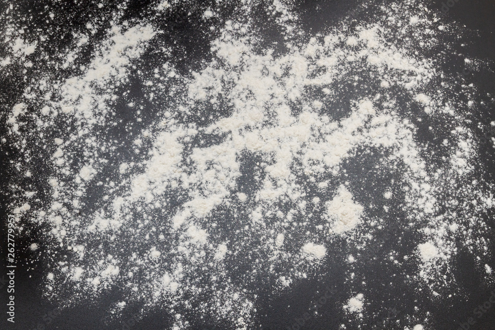 White flour is poured on a black table before cooking cookies White flour is poured on a black table before cooking cookies