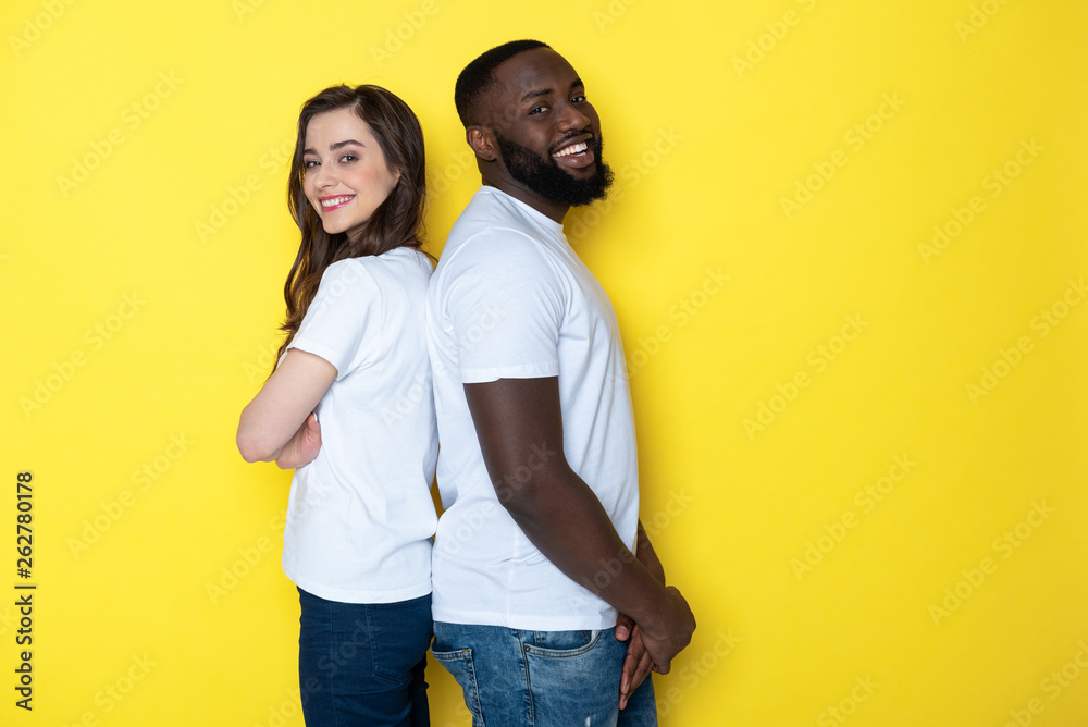 Smiling interracial couple in white T-shirts posing for camera in studio Smiling interracial couple in white T-shirts posing for camera in studio