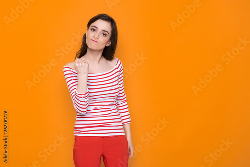 Waist up of angry brunette lady posing for camera in studio