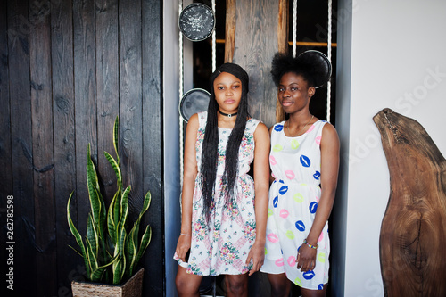 Two black african girlfriends at summer dresses posed indoor.