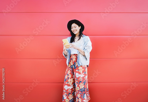Happy Asian girl using mobile phone outdoor - Chinese social influencer having fun with new trends smartphone apps - Generation z, media, technology and youth millennial people lifestyle