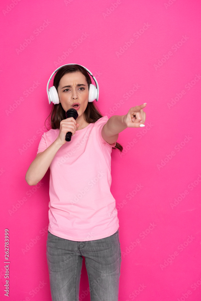 Cropped photo of serious Caucasian girl wearing headphones and holding microphone Cropped photo of serious Caucasian girl wearing headphones and holding microphone