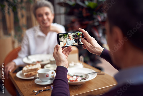 Man making photo of elegant lady on mobile phone