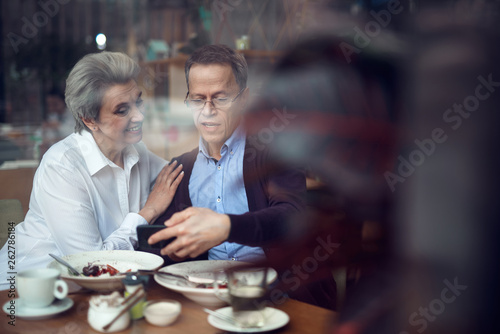 Mature couple look with interest in mobile phone