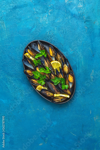 Seafood mussels with lemon and parsley in black metal plate