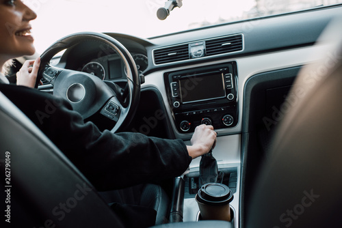 cropped view of cheerful woman holding gear shift handle while sitting in car