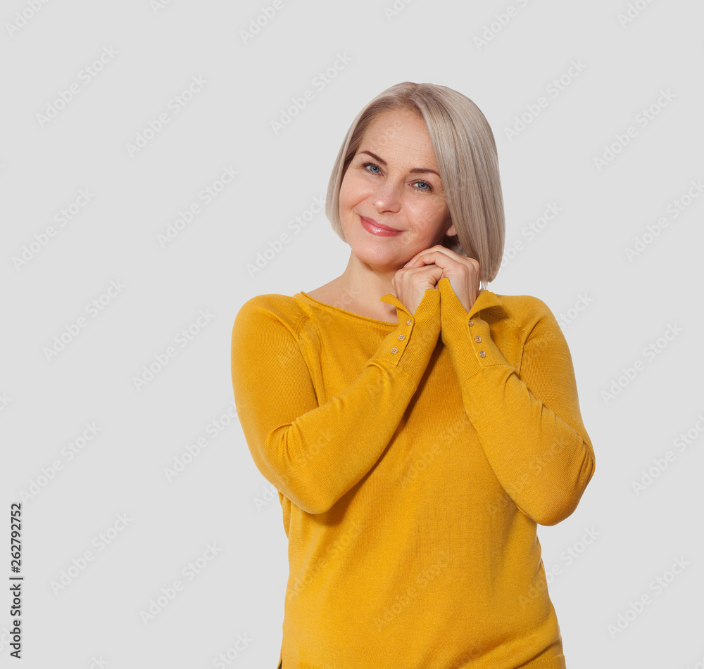 Middle aged blonde emotionally posing in a studio. Happy woman in yellow bright sweater on white background Middle aged blonde emotionally posing in a studio. Happy woman in yellow bright sweater on white background