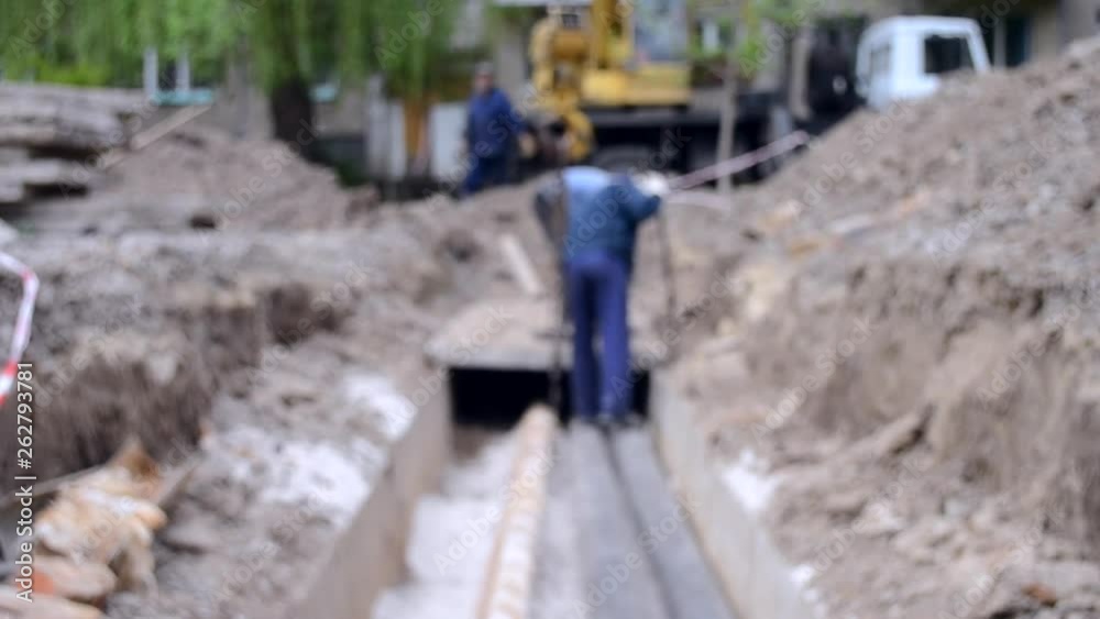 Workers with construction crane cover new water pipes with concrete slabs Workers with construction crane cover new water pipes with concrete slabs