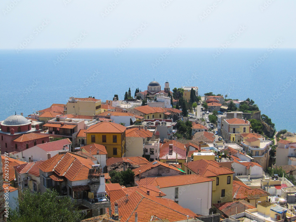Beautiful view of the old Greek city with red tiled roofs temple and endless blue sea on a hot Sunny summer day