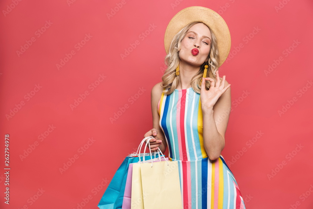 Amazing young woman posing isolated over red coral background holding shopping bags.