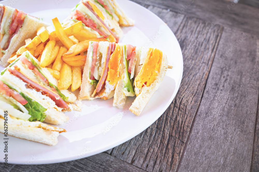 Club sandwich with bacon cheese and ham vegetable and sauce in white plate on table. Club sandwich with bacon cheese and ham vegetable and sauce in white plate on table.